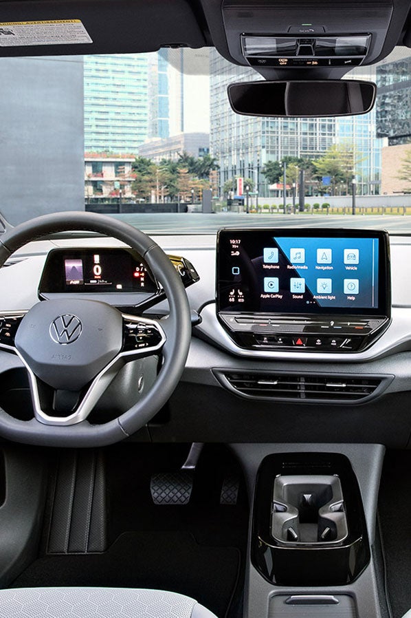 Interior shot of an ID.4 with focus on the front windshield, the dashboard, steering wheel, cup holder and center console display.