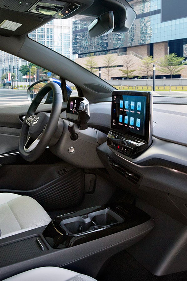 A shot of an ID.4 parked next to rock wall, with focus on the front seats, steering wheel, dash and center console display.